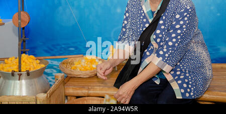 old woman & yellow silkworm cocoon shell for making thread producing Thai silk fabric textile Stock Photo