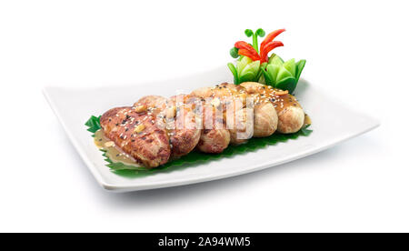 Grilled Bananas with Sweet Brown Sugar and Coconut Milk Sauce topped with sesame and peanut Thai Dessert decorate with carved cucumber ,chili vegetabl Stock Photo