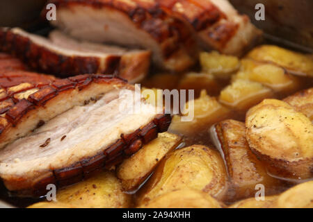 Homemade roast pork belly with fried potatoes sliced in juice close up