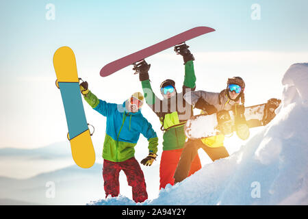 Three happy snowboarders are having fun and posing with snowboards Stock Photo