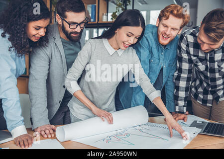 Startupers working together at office standing near table looking at performance graph cheerful Stock Photo