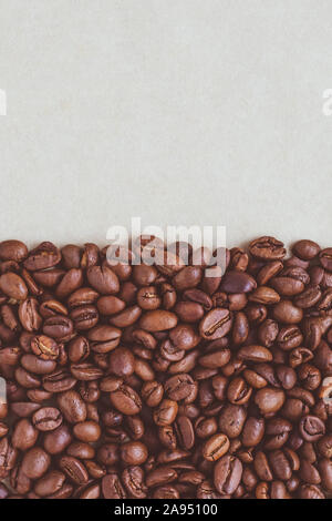 A heap of roasted coffee beans on a neutral paper background with copy space. Stock Photo
