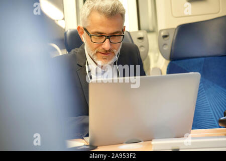 Businessman commuting by train, talking on phone Stock Photo