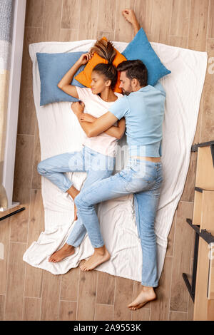 Mixed Race Couple. Young man and woman lying on bed top view hugging sleeping peaceful Stock Photo