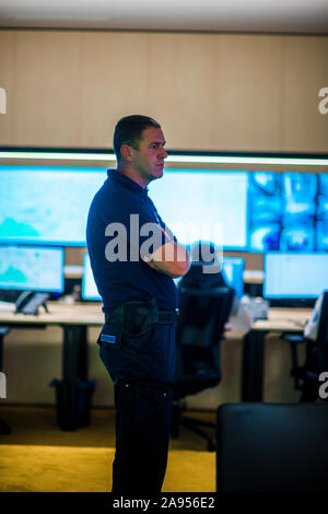 Security guards working in surveillance room with large screens. Stock Photo