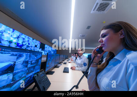 Technical Operator Works at His Workstation with Multiple Displays while talking on the phone, Security guards working on multiple monitors. Stock Photo