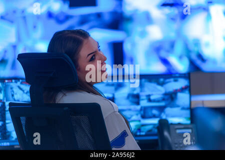 In the System Control Room, Technical Operator Works at His Workstation with Multiple Displays, Security guard working on multiple monitors. Stock Photo