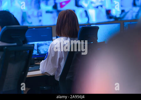 In the System Control Room, Technical Operator Works at His Workstation with Multiple Displays, Security guard working on multiple monitors. Stock Photo