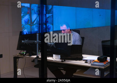 Side view of security system operator using walkie-talkie while looking at CCTV footage Stock Photo
