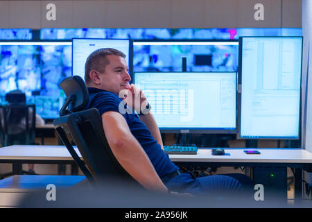 Side view of security system operator using walkie-talkie while looking at CCTV footage Stock Photo