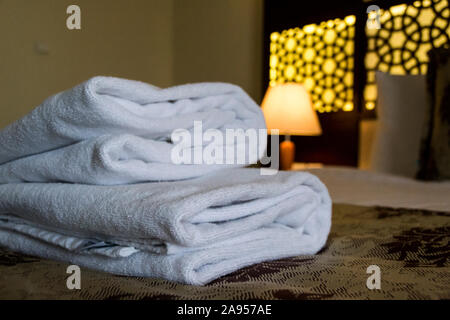 White towels on bed in a hotel room Stock Photo
