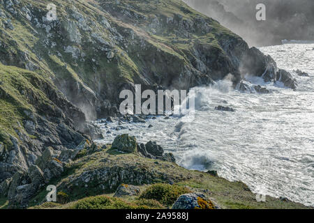 A very winterly wild and windy day brings the high seas crashing into the shoreline with great force down on the dramatic Lizard in Cornwall, England. Stock Photo