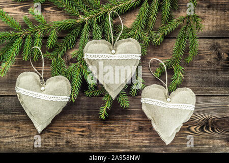 Textile decorative pillows in shape heart hanging on christmas tree branch Stock Photo