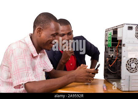 two technicians sitting at the desk working together on a computer Stock Photo