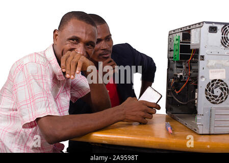 two technicians sitting at the desk working together on a computer Stock Photo