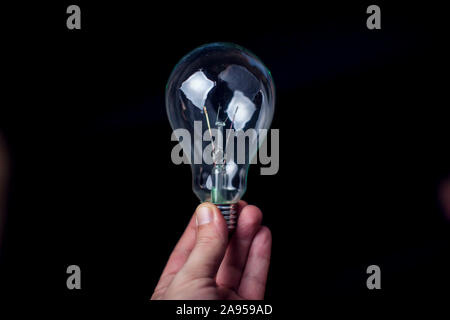 Light bulb in hand in front of black background. Energy or idea concept Stock Photo