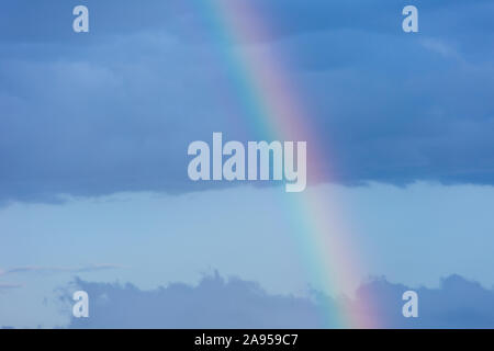A piece of rainbow in the sky against the background of rain clouds ...