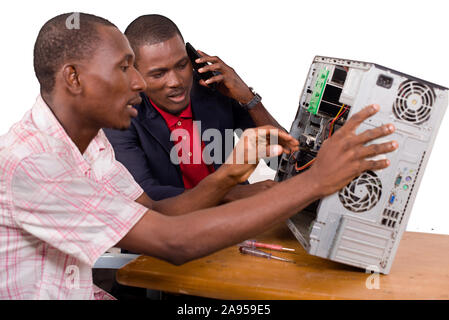 two technicians sitting at the desk working together on a computer Stock Photo