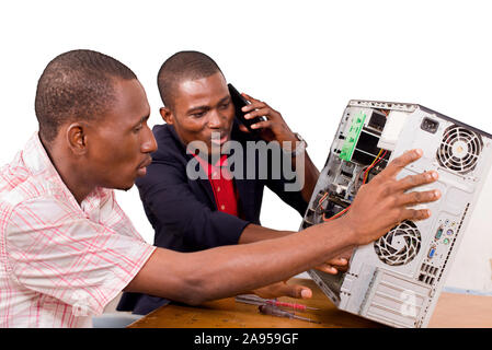 two technicians sitting at the desk working together on a computer Stock Photo