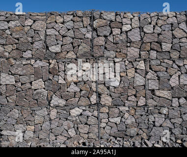 Large gabion wall detail on a sunny day against a clear blue sky Stock Photo