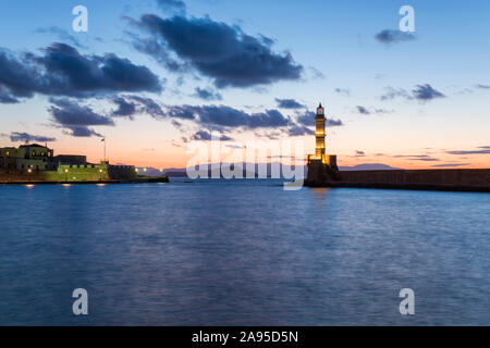 Chania, Crete, Greece. View across the illuminated Venetian Harbour at dusk, historic lighthouse prominent. Stock Photo