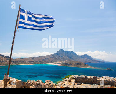 Imeri Gramvousa, Chania, Crete, Greece. View over Gramvousa Bay to the Gramvousa Peninsula, Greek flag flying from ramparts of the Venetian fortress. Stock Photo