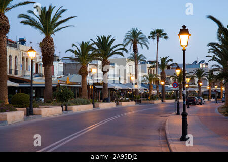 Rethymno, Crete, Greece. View along the illuminated palm-lined seafront promenade, dawn. Stock Photo