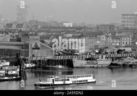 River Thames at Wapping, East London 1980s UK. Passenger ferry riverside industry, boatyards 1987. St Paul's Shadwell on horizon. 80s England HOMER SYKES Stock Photo
