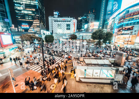 Tokyo, Japan - Nov 3, 2019: Crowded people walking, car traffic on Shibuya scramble crossing at night. Tokyo landmark tourist attraction concept Stock Photo