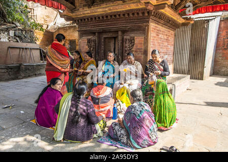 A group of Hindu women devotees in colorful sarees chanting prayers inside the Kathmandu Durbar Square in front of the main temple Stock Photo
