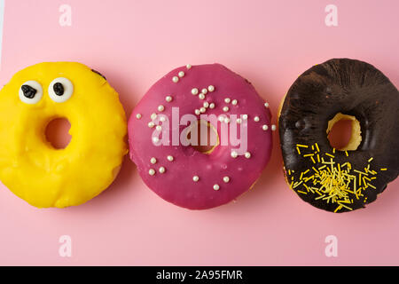 three round different sweet donuts with sprinkles on a yellow background, top view Stock Photo