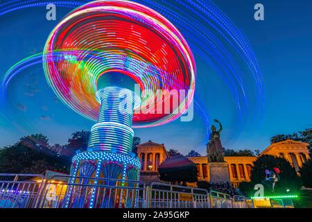 Rotating chain carousel at night in front of the Bavaria, Oktoberfest, Theresienwiese, Munich, Upper Bavaria, Bavaria, Germany Stock Photo