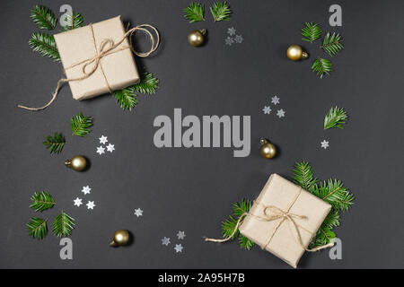 Christmas or winter composition. Handmade gift boxes decorated with craft paper of fir tree branches and confetti on dark background. Flat lay, top vi Stock Photo