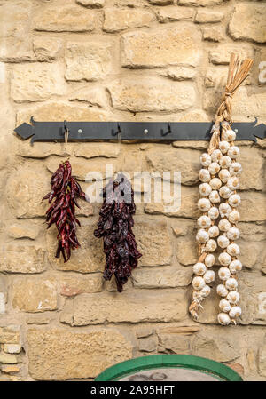Ristras of pepper pods and garlic bulbs on the stone wall Stock Photo