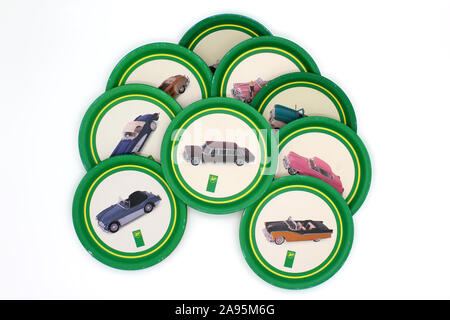 Vintage piled up stack of coasters metal plates with old cars illustrations, isolated on white background, close-up Stock Photo