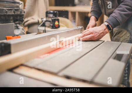 Carpentry workshop - carpenter works on a circular machine - cut bar Stock Photo