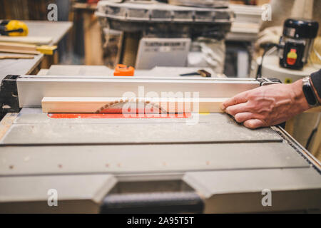 Carpentry workshop - carpenter works on a circular machine - cut bar Stock Photo