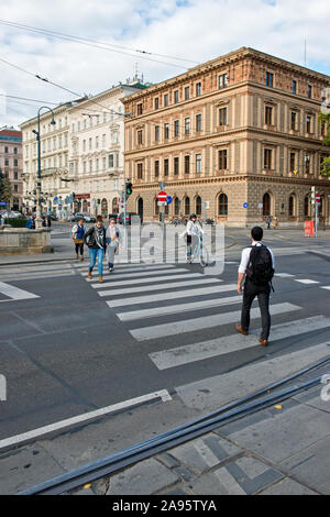 Pedestrians and cyclist crossing across busy street in central Vienna Stock Photo