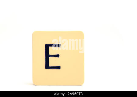 Dark letter E on a pale yellow square block isolated on white background Stock Photo