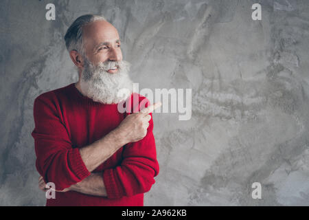 Photo of funny aged guy indicating finger empty space advising new product wear red knitted pullover hipster santa outfit isolated grey color wall Stock Photo