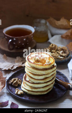 Vegetarian breakfast of fritters with honey, nuts and tea. Autumn still life. Stock Photo