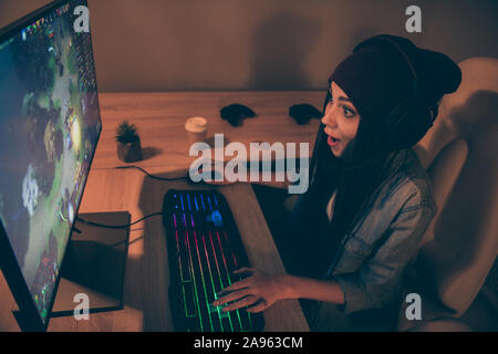 Top above high angle view photo of cheerful positive pretty sweet girl in cap headwear pressing keyboard with long brunette hair playing video game at Stock Photo