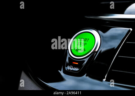 Car dashboard with focus on green engine start stop button. Modern car interior details. start/stop button. Car inside. Ignition remote starter Stock Photo