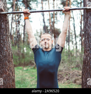 Man is doing pull-ups in the forest Stock Photo