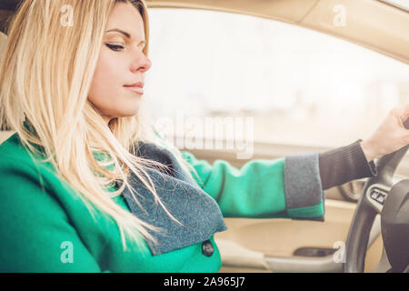The girl was distracted at the wheel - unsafe driving, mobile phone in the car Stock Photo