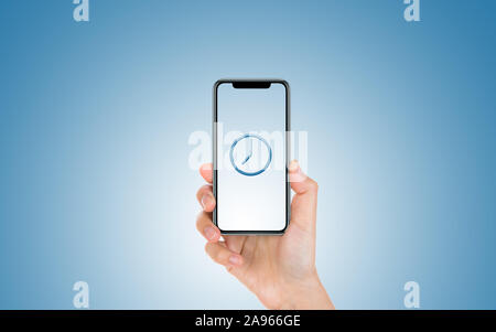 Male hand is holding and showing us a modern smart phone screen with airplane symbol against blue background. Business, finance, technology and money Stock Photo