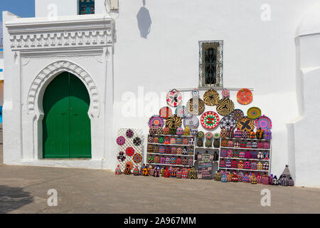 Asilah, Morocco-September 10, 2019: Colorful decorated souvenirs showed on a wall beside a traditional door in the medina of Asilah, Morocco Stock Photo