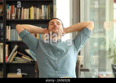 Front view of a relaxed man resting sitting with arms on head sitting in a coffee shop Stock Photo