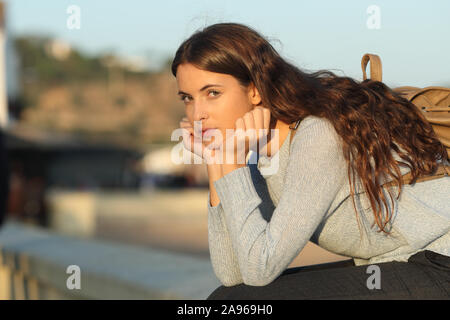 Portrait of a serious casual girl sitting in the street looking at camera Stock Photo