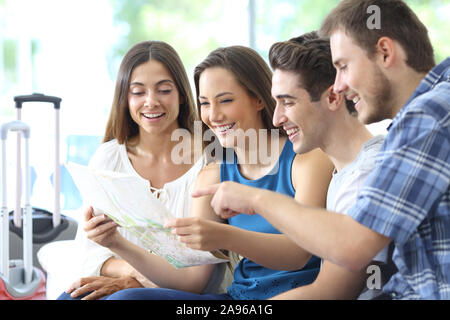 Group of tourists planning vacation checking maps sitting on a couch in the living room at home Stock Photo